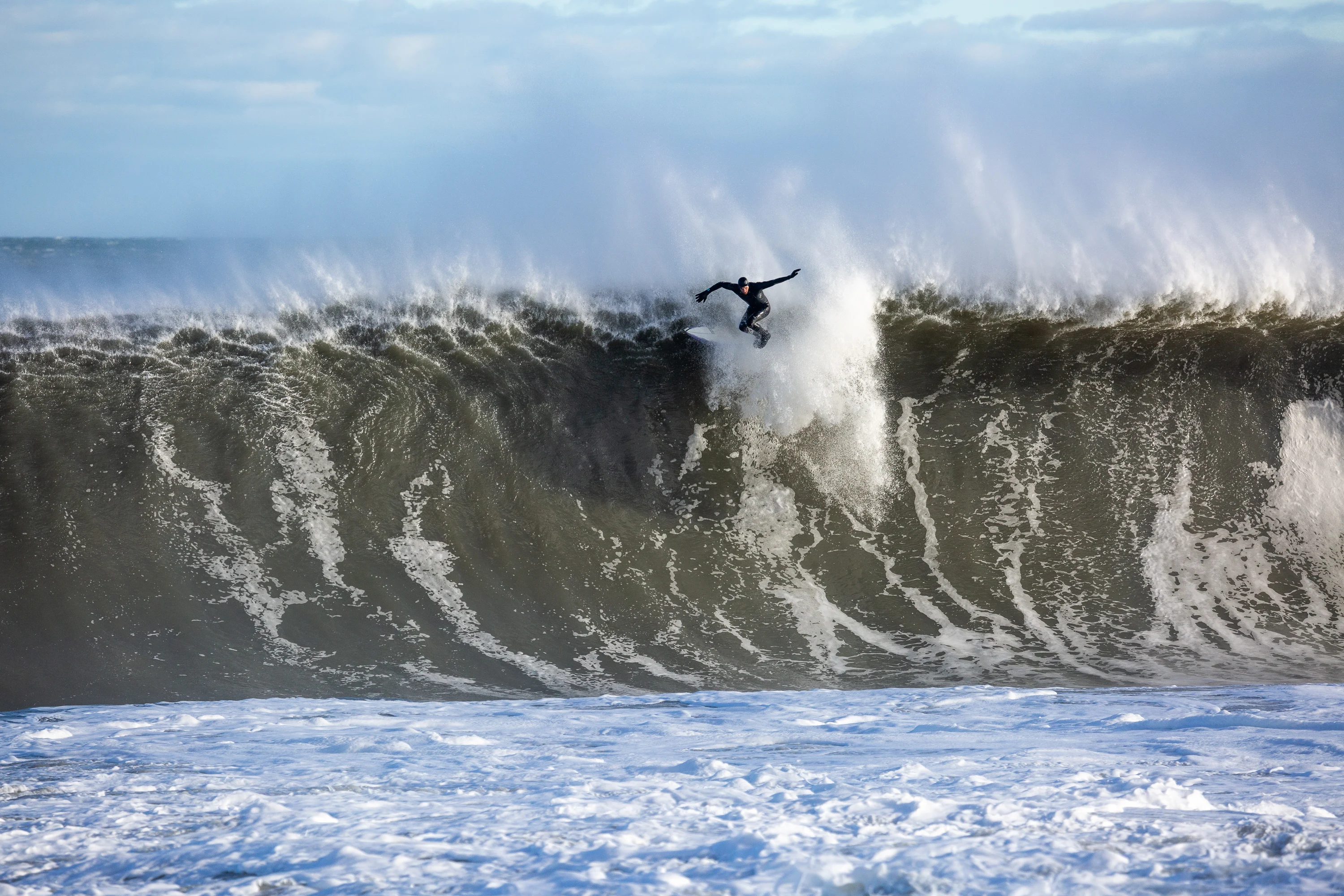 Surfer dropping into a big offshore-groomed wave on the New Jersey coast